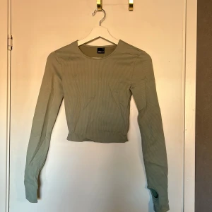 oanvänd blågrön tröja - jättefin och skön oanvänd topp i ribbat material. tycker den är grönblå i färgen med lite ribbat material. hål för tummarna. frakt ej inkluderat 
