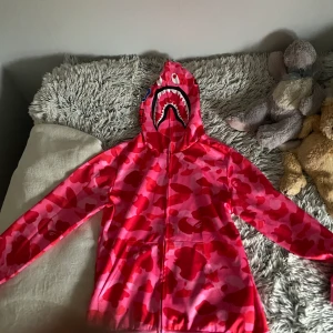 Rosa Bape Hoodie - En rosa jätte fin bape hoodie. Köpte för 550kr, säljer för att jag fick den i fel färg. Aldrig använd för jag fick den för 1 vecka sedan. Har kvar förpackningen som jag kan skicka med.