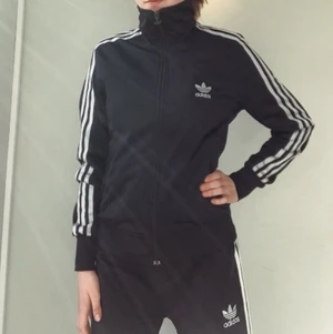 Adidas jacka - Svart adidas jacka med silvrigt adidasmärke på baksidan. Ränderna lyser i mörker. Knappt använd, jättebra skick.