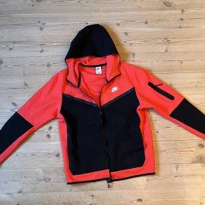 Nike tech fleece  - Röt och svart nike tech fleece i storlek L. Kommer aldrig till användning så är som gått som ny i skick! Köpt från Nikes egna sida 