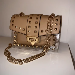 Väska  - Väska med nyskick. Justerbart kedje-band som gör att du kan ha den båda över bröstet och på axeln. Väska med avtagbart innerfack. 