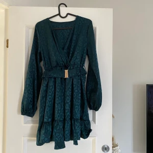 Klänning med bälte  - Snygg klänning i satintyg med bälte som framhäver midjan. Använd 1 gång!