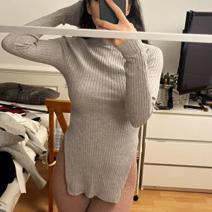 Tröja med slit - Tröja med liten krage, ribbat mjukt material och slit på båda sidorna. Formar kroppen.