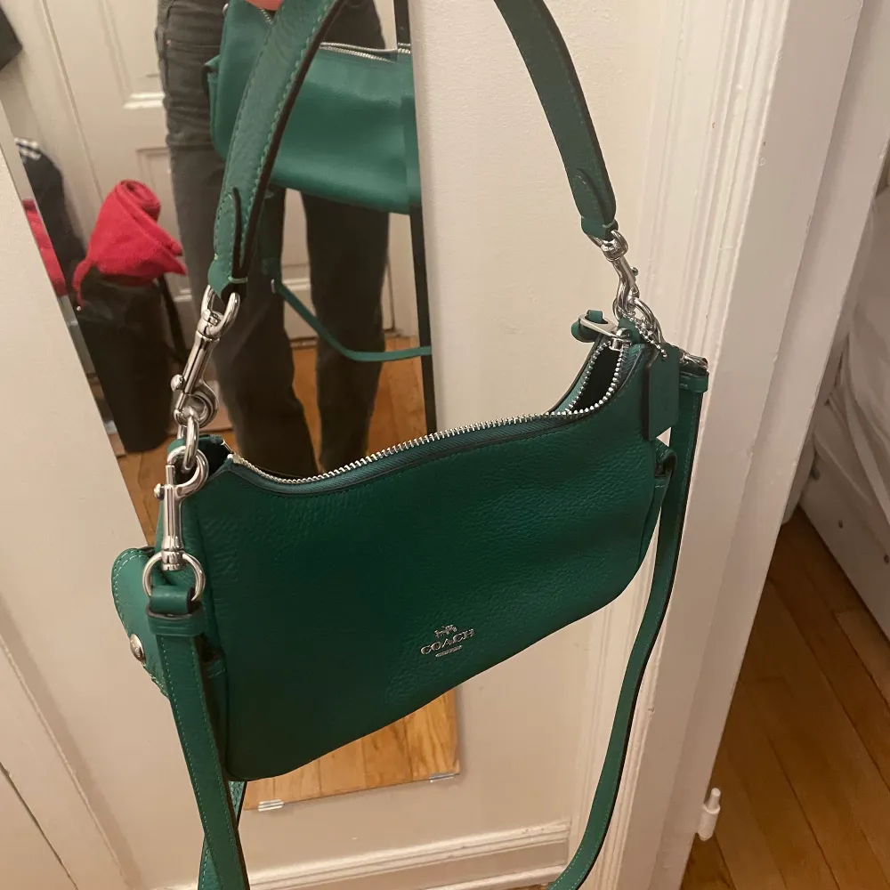 Ny fin coachhandväska i grön färg. Med kort band men även ett avtagbart längre band om man vill ha den som en axelremsväska. Inte använd och fick som en gåva. :) . Väskor.