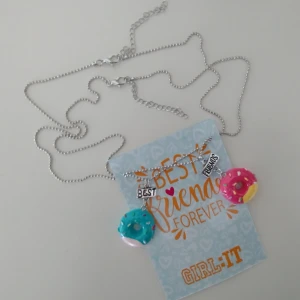 Två oanvända halsband/kulkedjor - vänskapshalsband - donuts 🍩 - Två oanvända vänskapshalsband. Silverfärgade kulkedjor i metall, med hängen i form av donuts. Ca 43+6 cm långa kedjor. Hängena är ca 4.2 cm långa. Fraktpris 15 kr. 