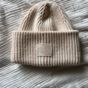 Ny stickad acne mössa beige  - Pupulär mössa i nyskick.  Köpte själv mössan här på Plick men den har tyvärr aldrig kommit till användning = helt ny. Hoppas att den kan komma till användning hos någon annan.  100% ull.  Osäker kring dess äkthet. 