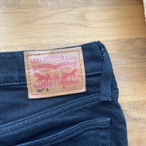 Levi’s 501 - Ett par i stort sett oanvända Levi’s 501 Jeans i svart. För mig passar de inte längre och har tyvärr kommit till för lite användning, varav den goda kvaliten. De är insydda någon centimeter i midjan som visat på 3:e bilden men som borde gå att ta bort🖤