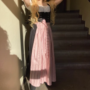 Äkta Dirndl oktoberfest xs Perul - Folkdräkt Från Bayern  Nypris 5000kr  Vit blues Svart klänning  Rosa förkläde Passar en smal person 32-34 Peruk säljes för 100kr helt ny guldblond 