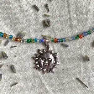 Halsband med små glaspärlor i blandade färger och en sol🤍