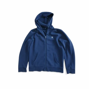 Ralph Lauren Performance Ziphood, str M - Jag säljer nu min Ralph Lauren tröja då jag har växt ur det. Tröjan är ungefär 1.5 år gammalt men skicket är bra. Passformen är bra och det sitter inte för tajt. Färgen på plagget är mörkblå. Nypris 1499 kr. Frakt tillkommer.