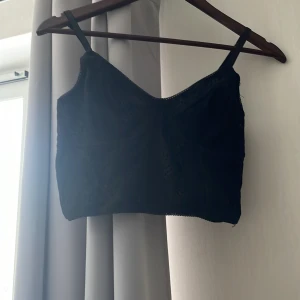 Topp - Svart topp med spets över hela tröjan, justerbara band och lite korsettliknande 