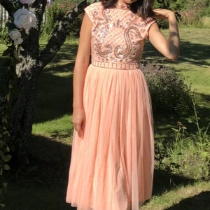 Rosa midi festklänning - Utsmyckad midi klänning i laxrosa färg, storlek 34/36. Endast använd i fåtal timmar, så gott som nyskick. Köpt från Zalando, finns ej kvar på sidan. Fler bilder finns