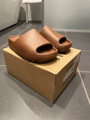 Yeezy slide ”flax” - Storlek 43 (små i storleken) Aldrig använda utan endast testade inomhus. Tags och kvitto samt original box medföljer vid köp. Yeezy blir mer svårt att få tag på efter att adidas sa upp samarbetet med Kanye West. Otroligt skön sko