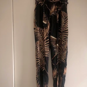 Kostymbyxor med palmmönster  - Dessa byxorna är svarta med ett beiget palmönster. Storleken är small. Byxorna är från H&M. Säljer de då de inte alls används.  (Frakten är inräknat i priset<3)