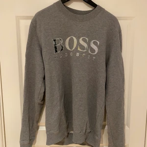 Hugo Boss Tröja - Storlek L - Hugo Boss sweatshirt i storlek L. Färg: Grå. Färgen har slitits bort på märket.