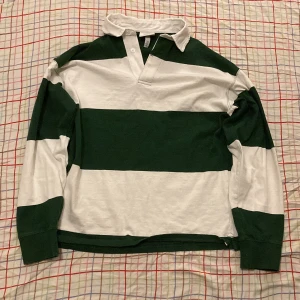 Grön-vit Rugbytröja - Köpt på H&M för 200kr. Strl S. Använt få ggr och jag säljer den för att den inte kommer till användning och så är det inte riktigt min stil längre. Står tyvärr inte för frakt.