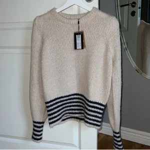 Ljus stickad tröja med ränder - Säljer denna supersköna stickade tröjan helt oanvänd med lapp. Köpt för 399 kr på Nelly, helt slutsåld! Storlek L men skulle säga passar XS-M bättre, den är mjuk🫶🏽 pris kan diskuteras 