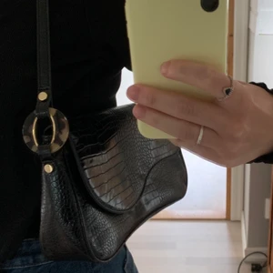 Axelväska i krokodil - Axelväska i krokodilmönster från Asos. Fint skick 🌷 får plats med mobil, nycklar och en bok ca för att få en bild av hur stor den är då den är ganska avlång 