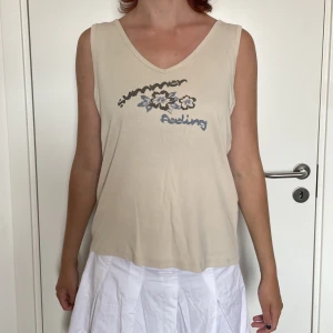 Linne med tryck  - Beigt V-ringat linne med tryck på framsidan. 