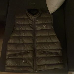 Moncler gui väst  - Säljer min Moncler gui väst storlek Xl  Har bevis på att den är äkta inget kvitto kvar men den har alla tags  Finns en liten skada Annars fint skick 8-10 