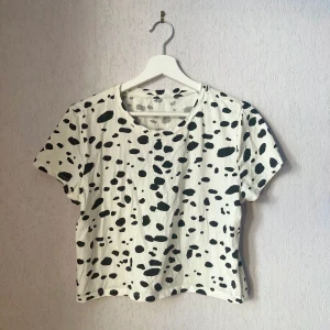 Kort prickig topp - Kort prickig t-shirt med dalmatinmönster.  Storlek S. Märke: Monki, men lappen är borta.  Inga defekter/fläckar. T-shirten är i mycket gott skick.