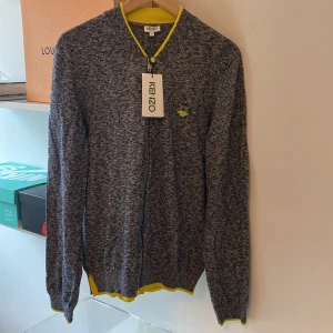 Kenzo tröja - En kenzo tröja grå med gula detaljer i storlek L men lite liten i storleken, Aldrig använd med lappen kvar. Ny pris 2999