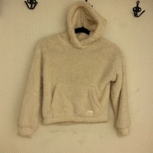 Myströja ”fluffig” - Fin tröja i vitt. Ficka på magen. Luva. Riktig myströja.  Köparen står för frakten. Jag ansvarar inte för postens hantering. Jag visar bild på när jag skickar paketet. Vid fler intressen av objekt kan bud över begärt ingångspris läggas.