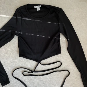 Tröja med knytning - Säljer denna ursnygga tröja, knappt använd. Vet inte riktigt vart den är ifrån men märket är amisu💕 Den ser grå ut på andra bilden men är svart💕