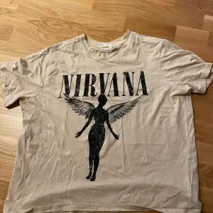 Snygg beige graphic Nirvana t-shirt! Säljer då jag inte använder den längre, fortfarande i bra skick. Storlek L men passar som M/L!