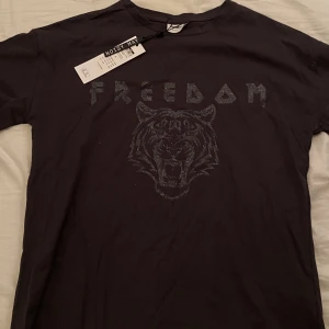 Svart T-shirt med glitter tryck - Svart T-shirt med glitter tryck från Noisy May i storlek ”S”. 