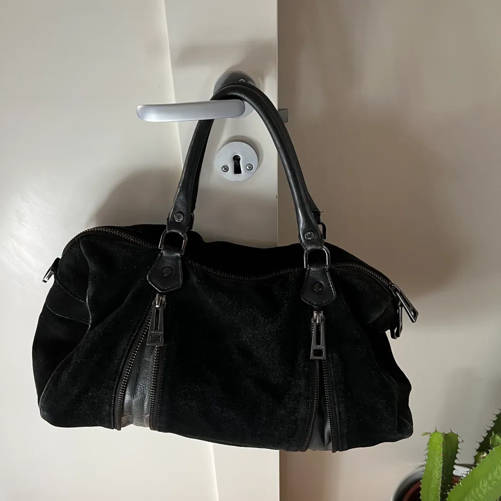 Zadig et Voltaire Sunny bag i större modell. Väskan är i svart mocka med vissa svarta läderdetaljer. Den har används en del och vissa mockapartier är därför lite slitna, men det går säkert att fixa med en mockavätska och väskan är i helhet i bra skick.. Väskor.