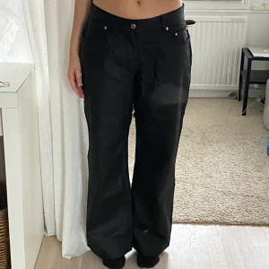 Svarta vida lågmidjade byxor i läderimitation  - Supersnygga lågmidjade vida byxor i läderimitation!! Perfekta för att gå ut eller klä upp en vardagsoutfit! Avslappnad passform med fyra fickor. Köpta från Asos, hann inte returnera. Kan mötas upp eller skicka på post, köparen står för frakten🥰