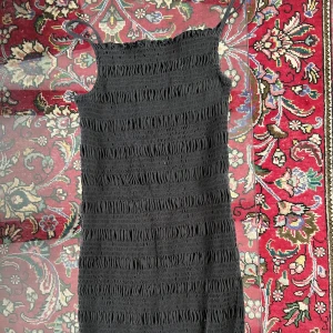 Klänning - En svart tight klänning som går att både klä upp och klä ner. Den slutar på låret och är i gott skick. 