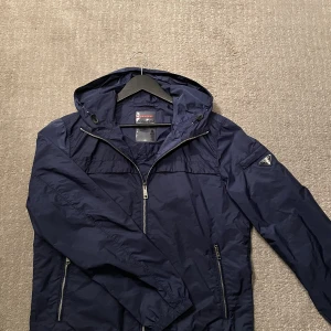 Prada windbreaker  - Säljer en Prada windbreaker i en väldigt fin blå färg i bra skick! Den har ett litet hål längst ner vid armen, kan skicka bild privat på det! Men annars är skicket 8/10. Storlek 50 vilken motsvarar S/M!  Självklart äkta! Hör gärna av dig om du har frågor!