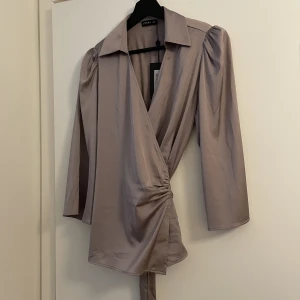 Omlottblus satin  - Aldrig använd, prislapp kvar.  Storlek M. Nypris: 599kr