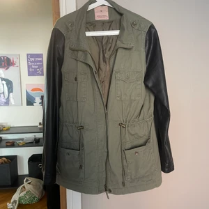 Jacka  - En använd grön jacka med svarta skinnärmar, väldigt snygg! 