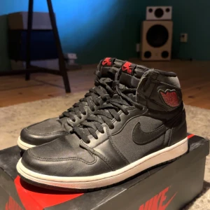 Jordan 1 Retro High Black Satin Gym Red - Säljer nu mina Jordans, då jag inte har någon användning av dem längre. Storlek 44 (US 10), Skick 8/10, Inköpta från SNKRS appen (Kvitto finns), Dem röda snörena medföljer (Helt nya), Lite smutsiga på det vita men annars felfria.  