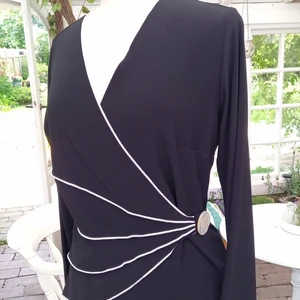 Svart omlott topp - Stretchtyg i svart polyester Omlott topp med mycket kvinnlig passform. Lång ärm Använd 1 gång 