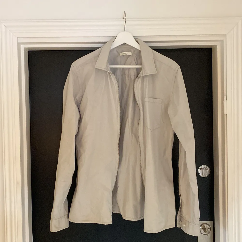 En ljusgrå jacka/overshirt i storlek M, har en liten fläck på ryggen annars fint skick!. Skjortor.