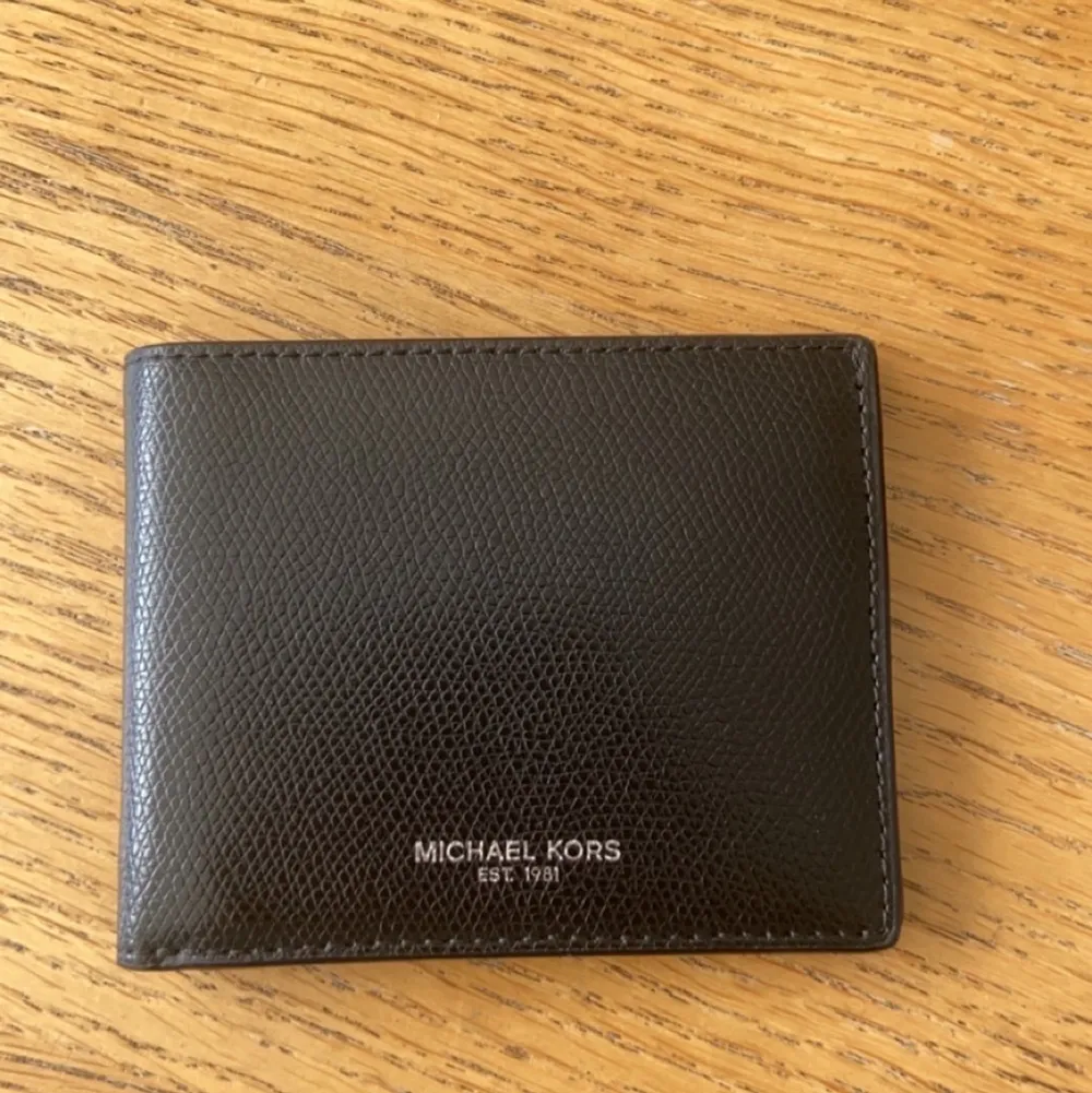 En skitsnygg Michael Kors plånbok med låda, som aldrig blivit använd. Kondition: 9.5/10. Väskor.