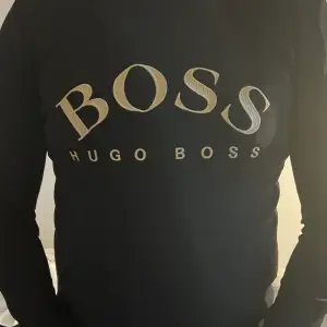 Snygg svart boss tröja med guldiga detaljer i storlek L