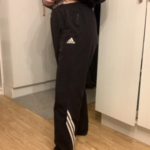 Adidas tracksuit byxor - Adidas byxor ”tracksuit” material. Finns inga lappar kvar men uppskattar till stl XL Midjemått rakt över: 50cm.  Längd: ca 107 cm (passat mig som är 167cm)  Resårband invändigt så byxan går att spänna åt