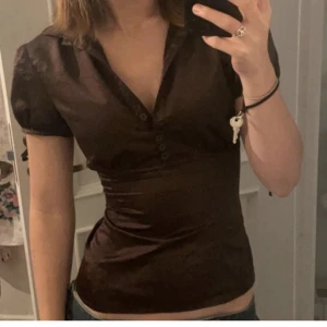 Silkes blus - Brun blus i silkes material, super söt och verkligen får fram formerna på kroppen. Älskar verkligen men måste tyvärr rensa garderoben💗storlek XS/S