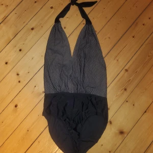 Body med öppen rygg - Body från Bikbok med öppen rygg, V-ringad och knyts bakom nacken. Sparsamt använd, fint skick. Beige färg med nät i överdel, svart blank underdel likt baddräktsmaterial. Okej att komma med bud. 