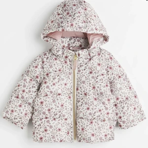 Barnjacka - Helt ny och oanvänd, taggen på. Ordinariepris 250kr. En vadderad pufferjacka i quiltad, vävd kvalitet. Jackan har stäkrage och dragkedja med hakskydd som minskar risken för skav. Avtagbar huva. Dold resar vid ärmslut och i nederkant. Fodrad. Gratis frakt!