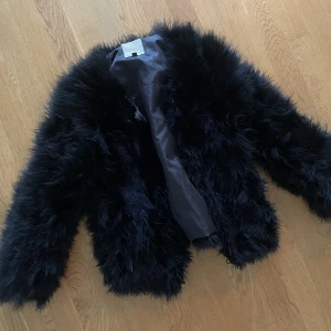 Fake pälsjacka med fjädrar svart strl s - Fake pälsjacka med fjädrar svart strl s
