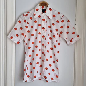 VINTAGE RETRO blus med äpplen  - Hur söt är inte denna?! Vit blus med röda äpplen. Doftar 60-/70-tal lång väg! VDN-märkningen tyder på god kvalitet och att den är tillverkad senast 1973. Uppskattas passa stl XS / S / 34 / 36.