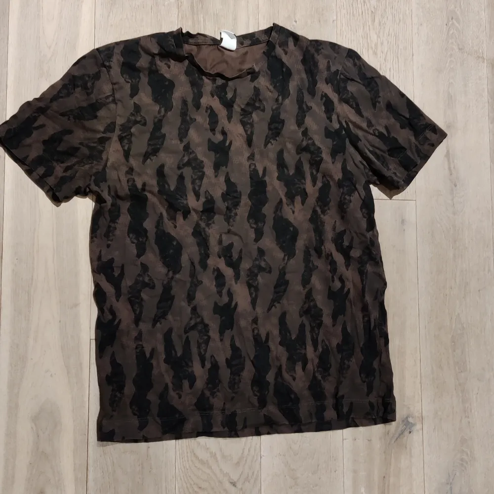 Sparsamt använd t-shirt från visual clothing project. Snyggt brun/svart mönster. T-shirts.