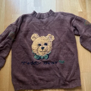 Brun stickad tröja - Gullig stickad tröja som det står Teddy bear på! Har lite färgskiftning(se andra bilden) men det är inget man tänker på! Köpt secondhand men utan lappar så gissar på att någon stickat den själv! Gissar att den är ung. en större small 