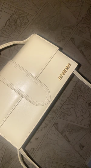 Jacquemusbag - Jacquemus väska ( Le bambinou bag) med en axelremsa i färgen gul/beige. Jättesnygg classy väska. Väskan är även i normal storlek samt oanvänd. Hör gärna av er vid frågor eller funderingar. Pris kan även diskuteras:)